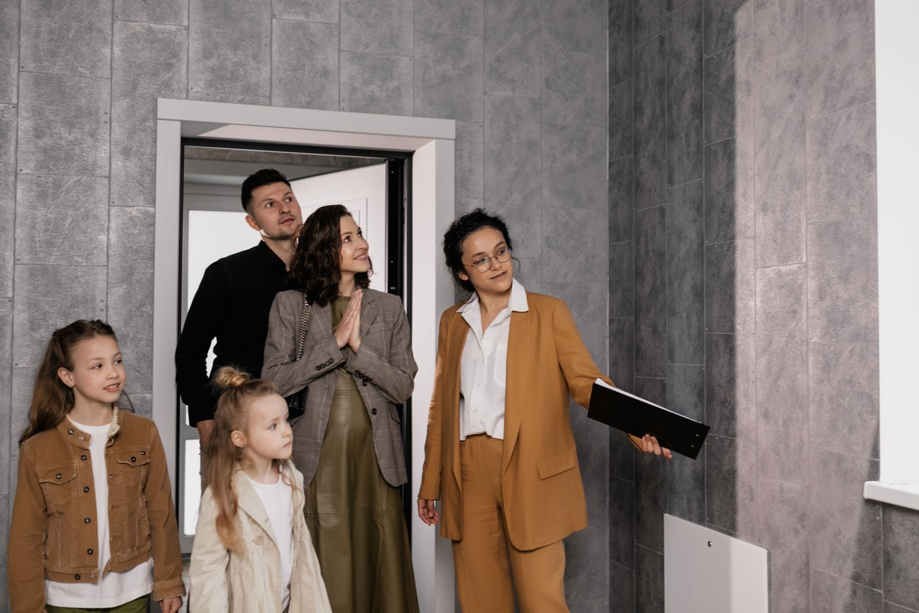 A family with children tours a new house guided by a realtor. Ideal for real estate themes.